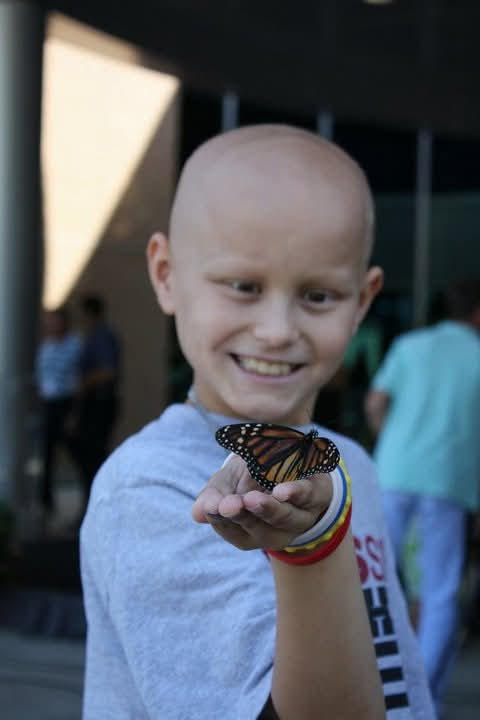 Bryan holding a monarch butterfly during childhood cancer treatment