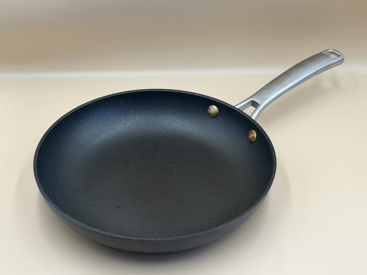 A black everyday frying pan with a metal handle