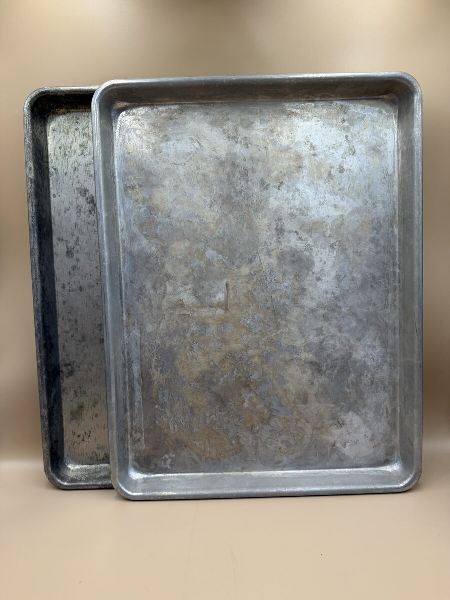 Two well-used large aluminum baking sheets